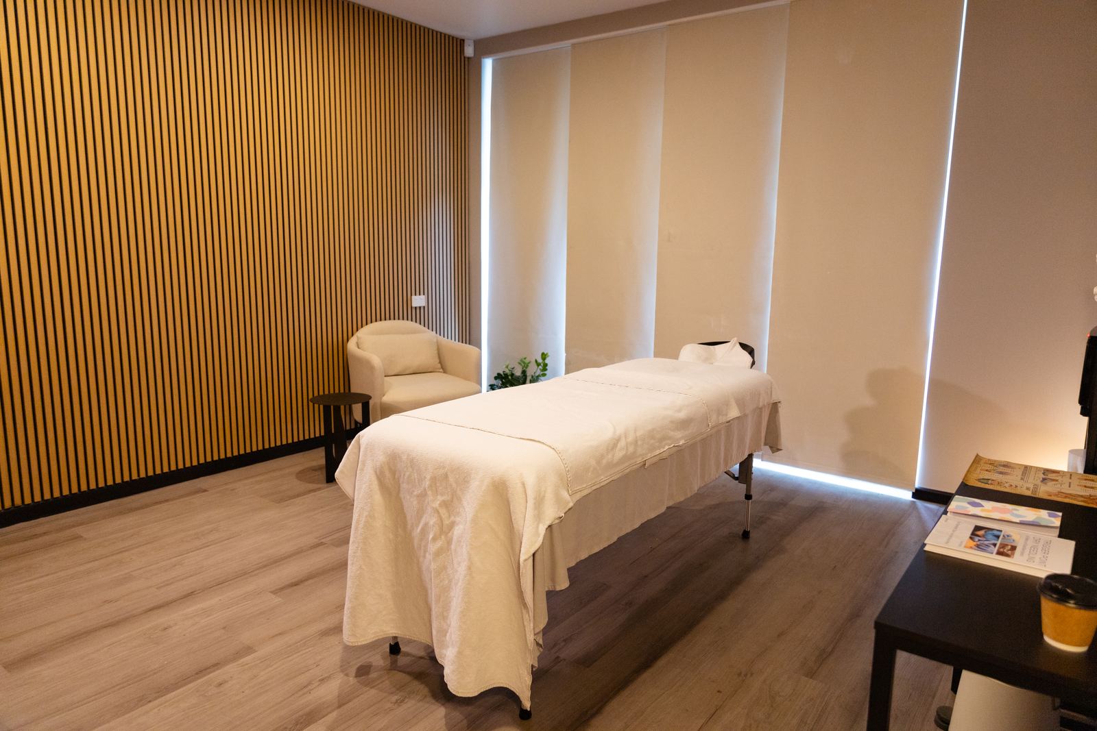 The Strong Hands treatment room, with a massage table, armchair and wood-slat wall